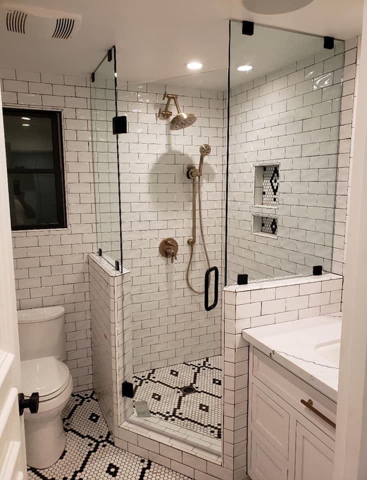 Frameless glass shower enclosure with matte black hardware in a white subway tile bathroom