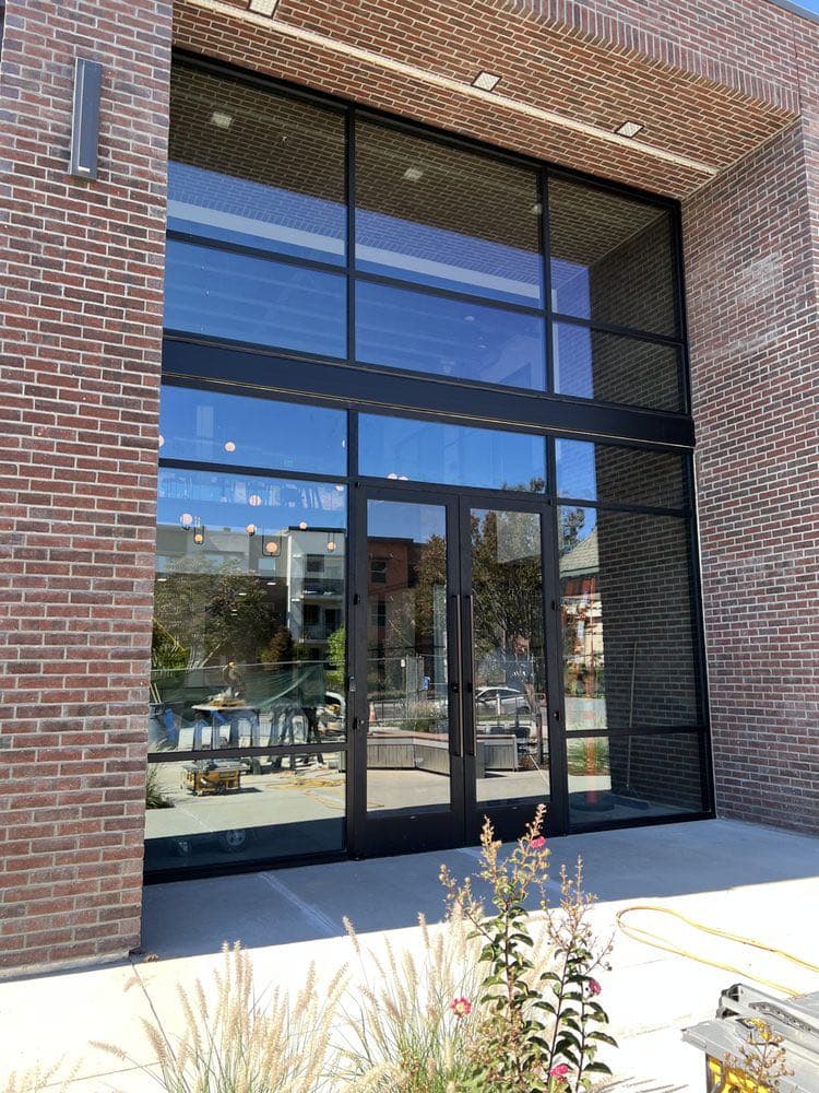 Two-storey storefront glass wall in dark aluminum framing on a brick commercial building