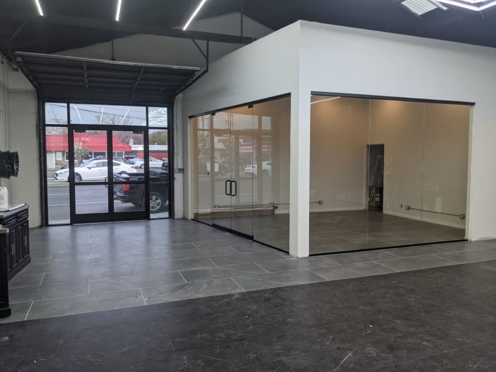 Retail interior with aluminum storefront entry doors facing the street and a frameless glass partition wall